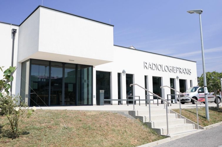 Außenansicht der Radiologiepraxis Oberpullendorf mit modernem Gebäude, Eingangsbereich und Praxisbeschriftung.