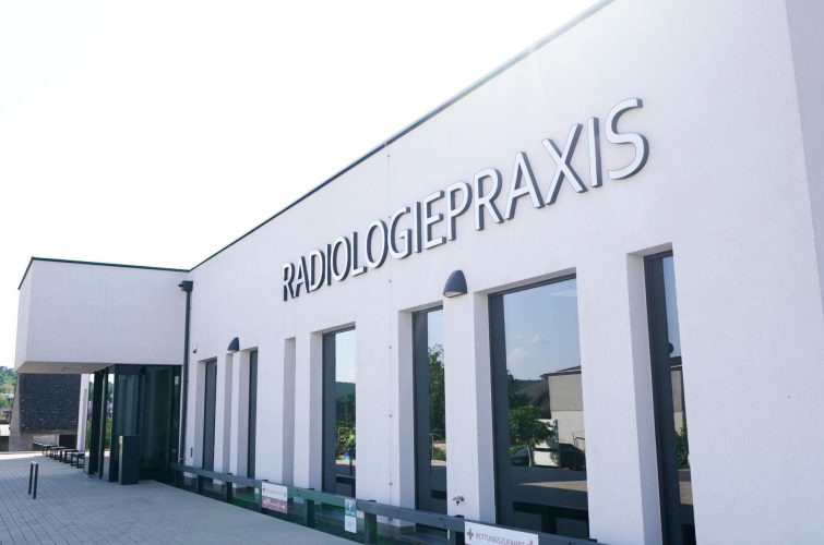 Außenansicht der Radiologiepraxis mit modernem Gebäude und großer Beschriftung an der Fassade.